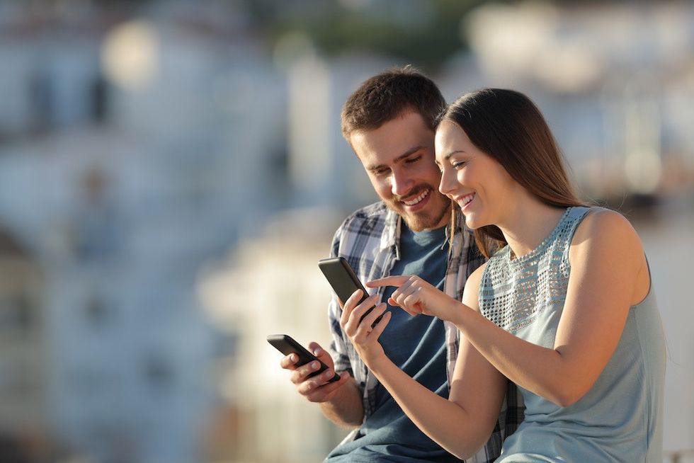 Smiling couple looking at a smartphone together outdoors.