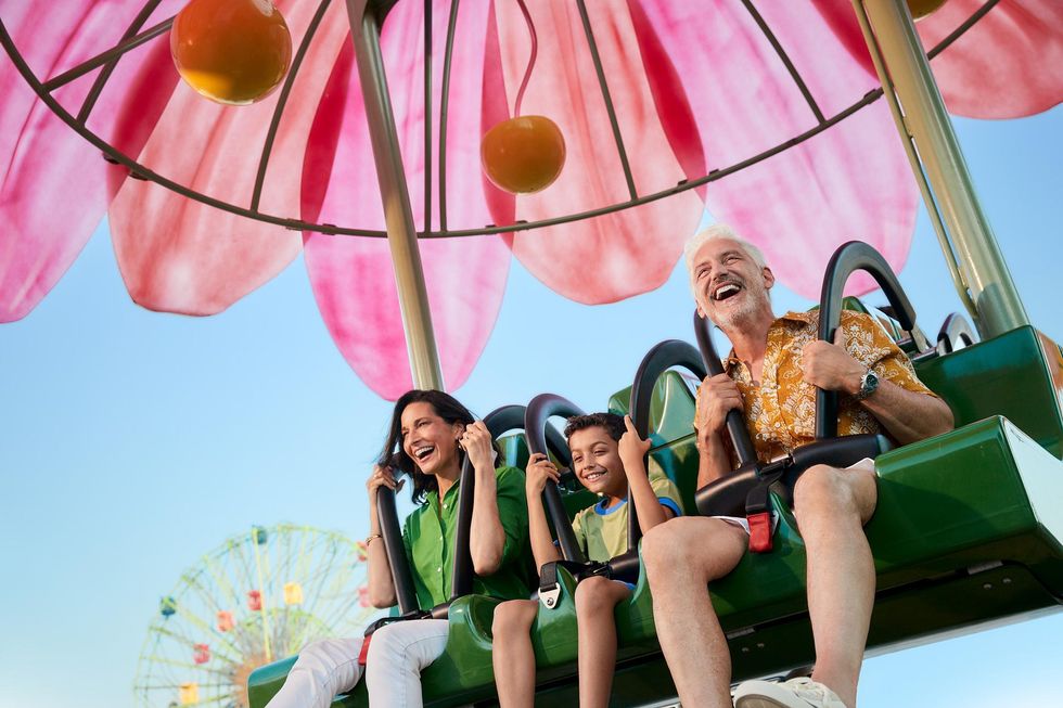 Smiling family enjoying a colorful ride under a flower canopy at an amusement park called BON in Mexico