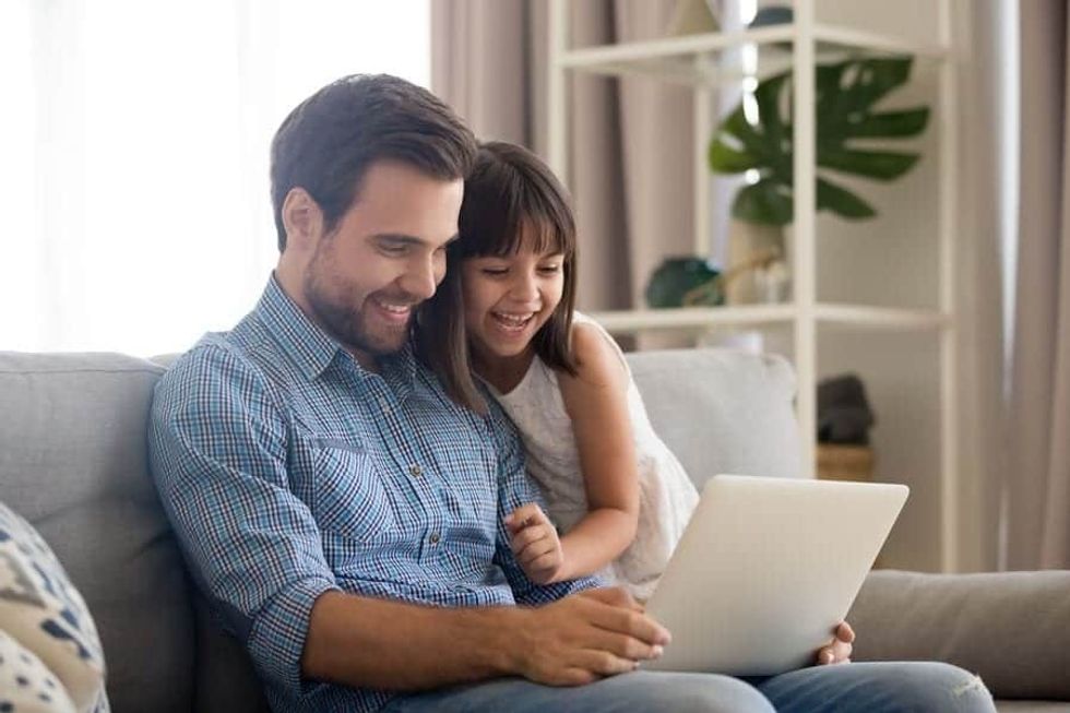 Smiling father and daughter looking at a screen