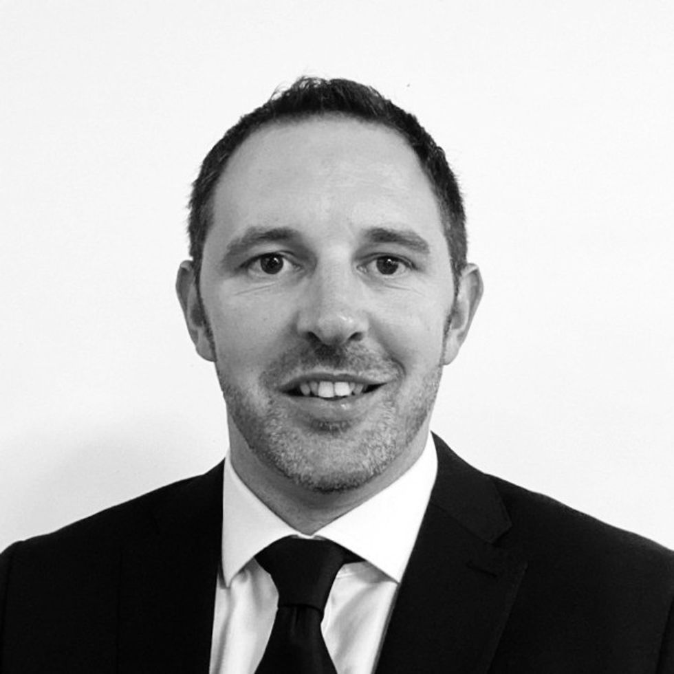 Smiling man in a suit and tie, black and white portrait.