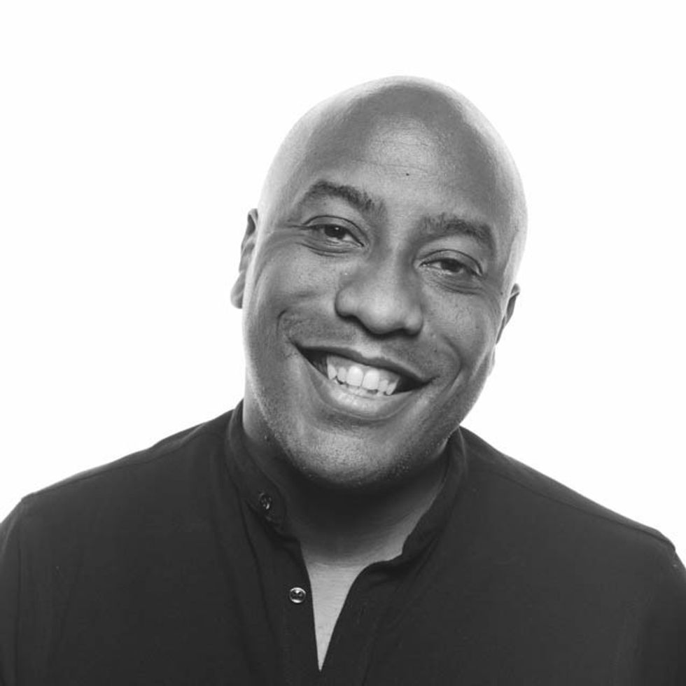 Smiling man in black shirt named Dan Picard, monochrome portrait.