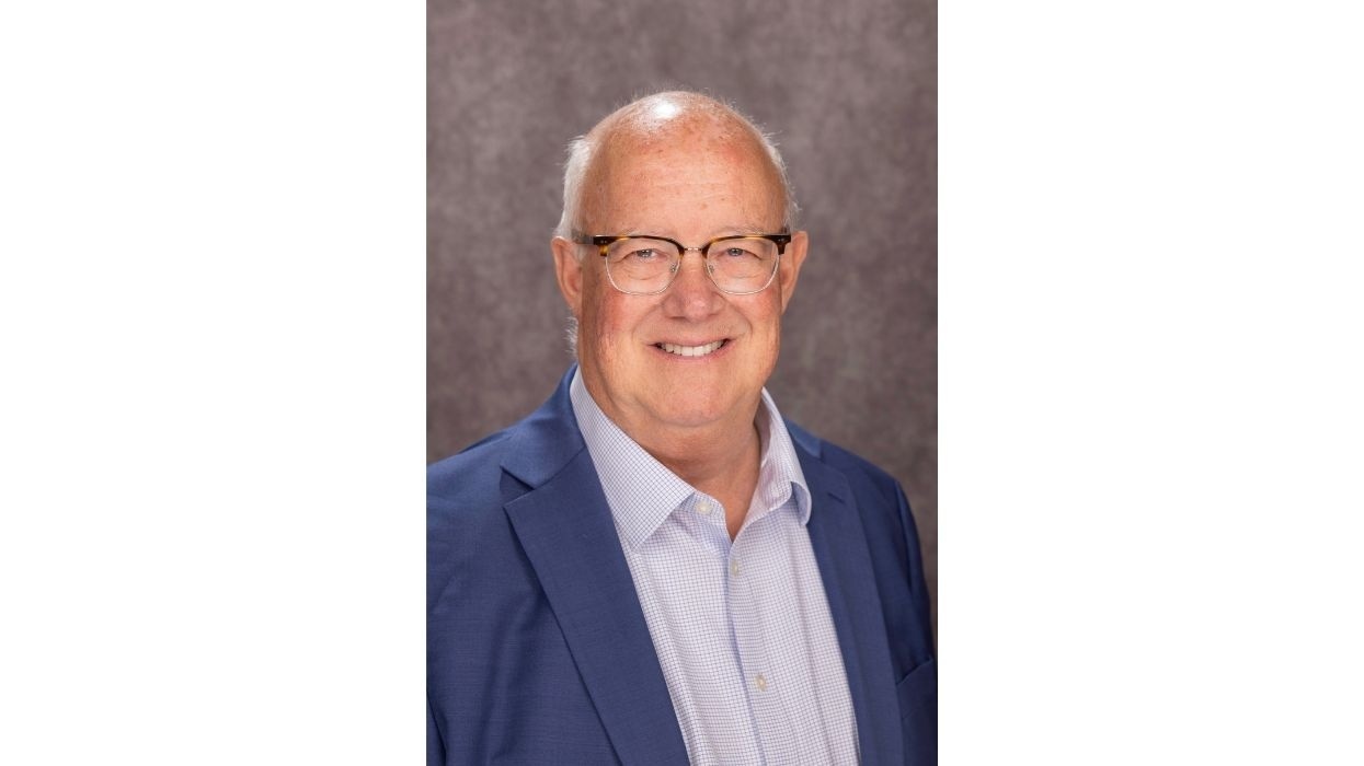Smiling man named Matt Conover, in glasses and suit, with a gray background.