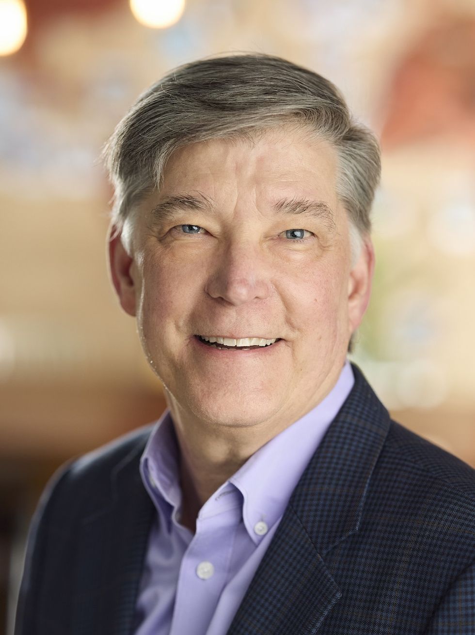 Smiling person in a suit with a blurred background.