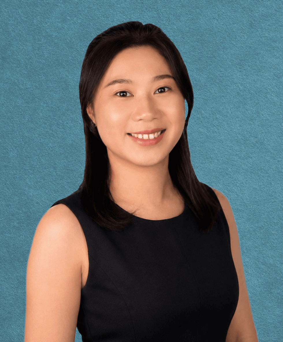 Smiling person with long hair in a black top, blue textured background.