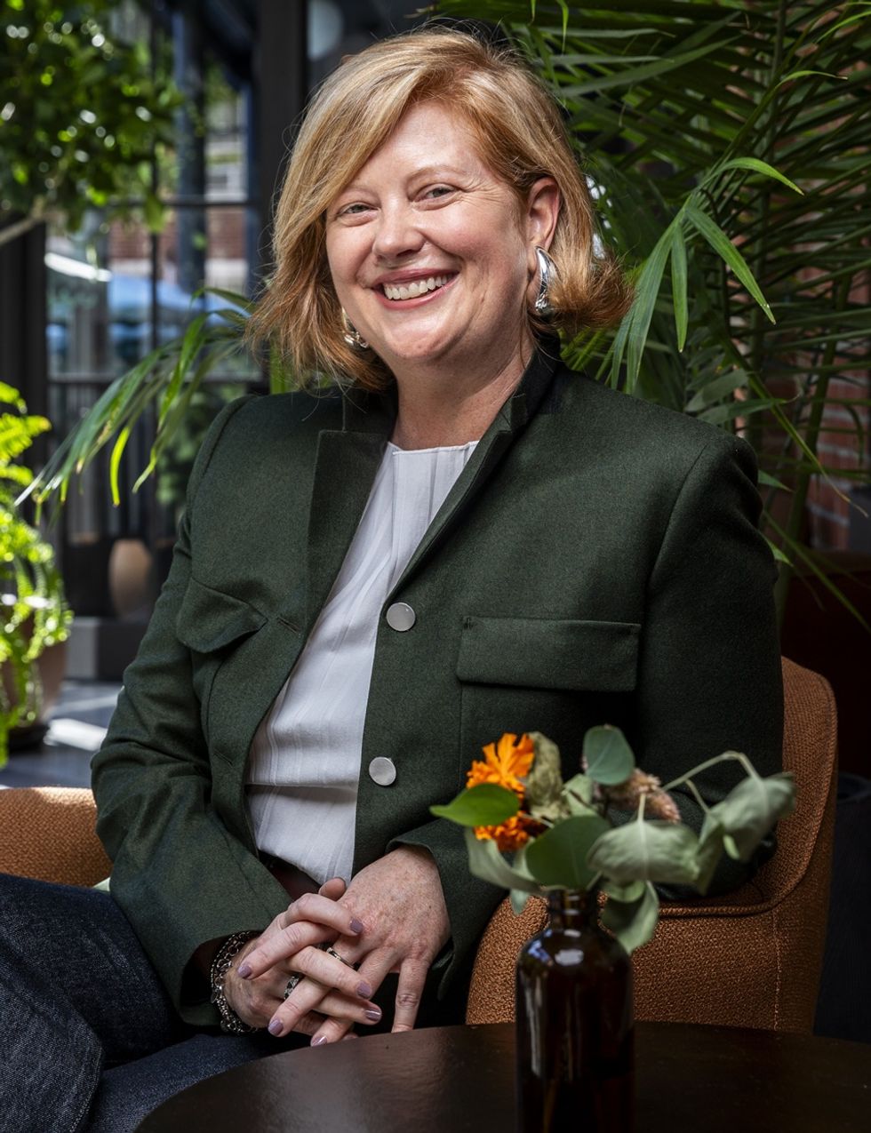 Smiling woman named Abby Bysshe in a green jacket with plants in the background.