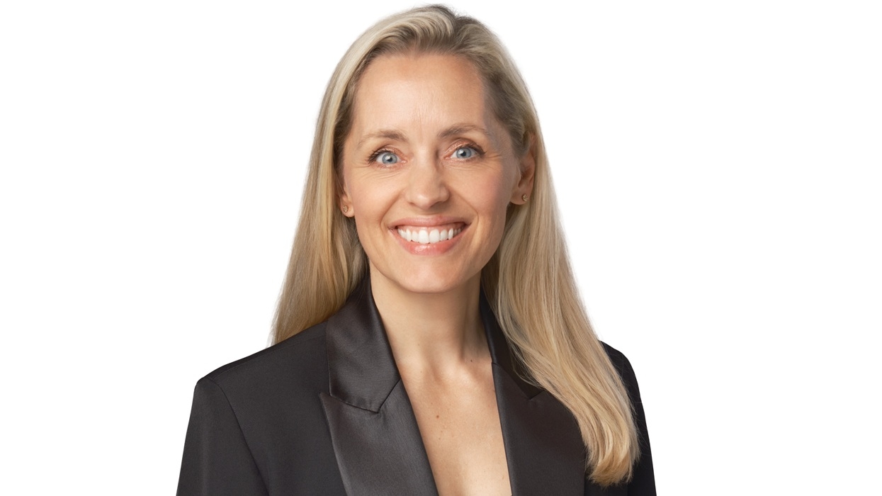 Smiling woman named Angie Judge with long blonde hair in a black blazer on a white background.