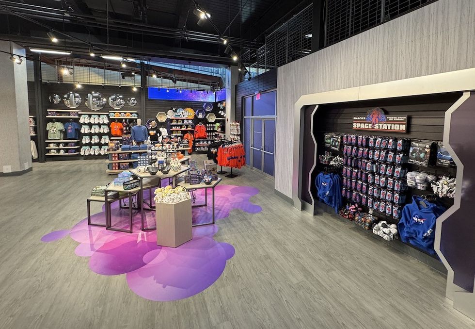 Space-themed gift shop with clothing, toys, and space-themed merchandise on display.