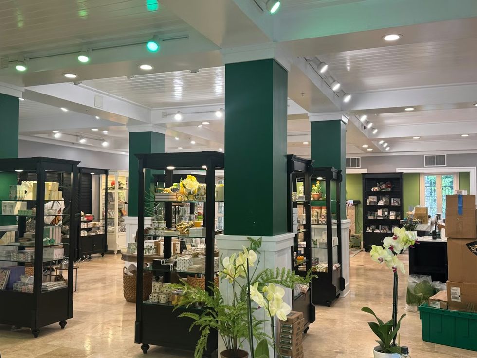 Spacious store interior with green walls, display shelves, and decorative orchids. The Sanctuary Shop at Fairchild Tropical Botanic Garden