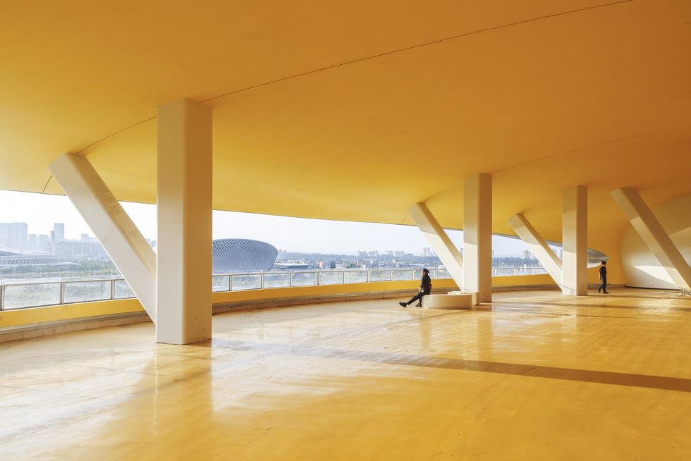 Spacious yellow architectural interior at the Hainan Science Museum with large windows and cityscape view.