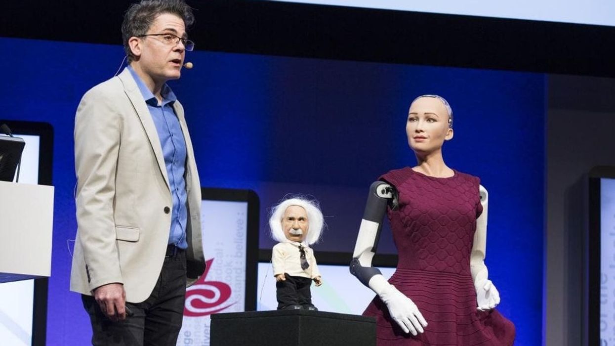 Speaker at IBC with mini figure of Einstein and female robot