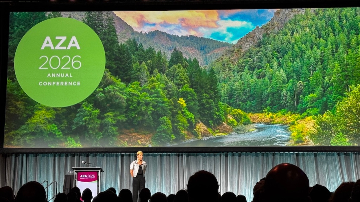 Speaker on stage at AZA 2026 conference with nature backdrop.