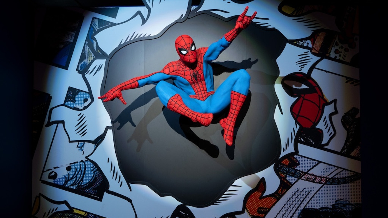 Spider-Man in dynamic pose, emerging from a comic-style background wall.