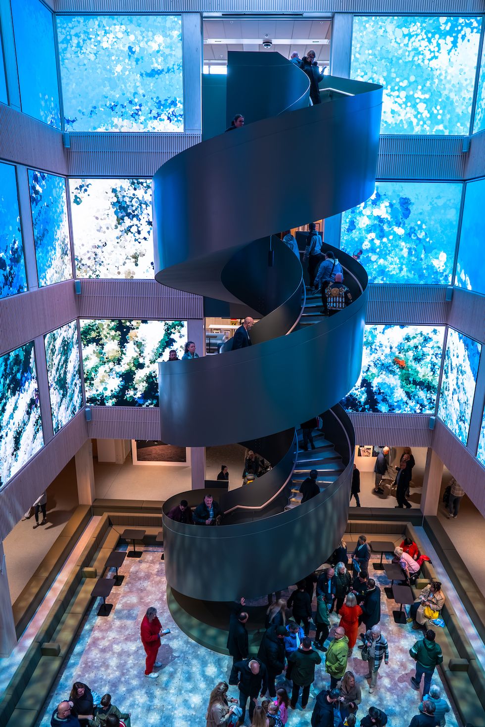 Spiral staircase in vibrant modern atrium, with people ascending and descending.