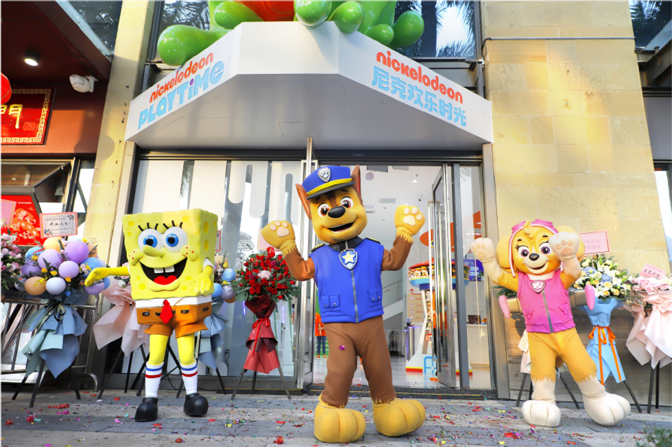 SpongeBob and Paw Patrol characters outside a Nickelodeon store with festive balloons.