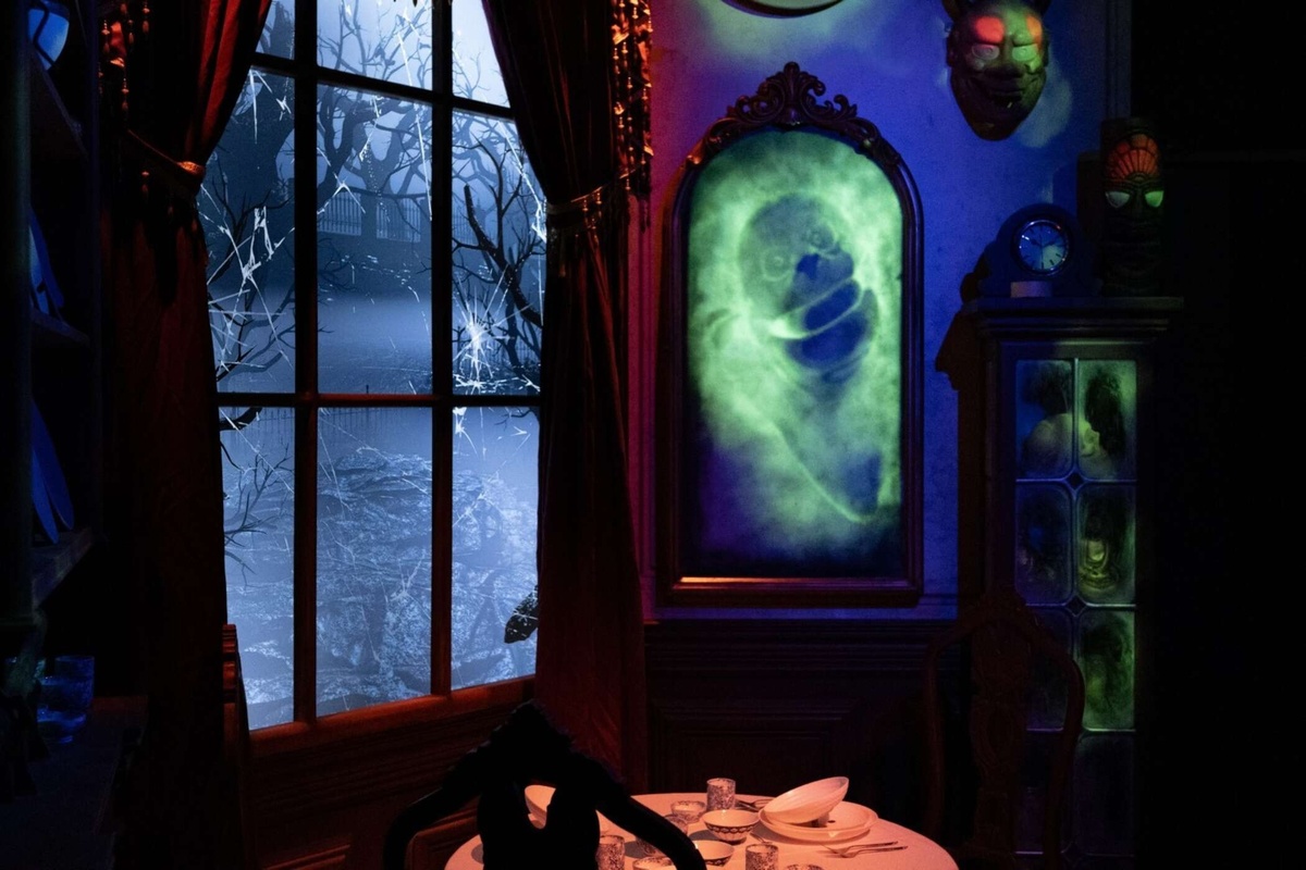 Spooky room with glowing ghost portrait, eerie masks, and moonlit window scene.