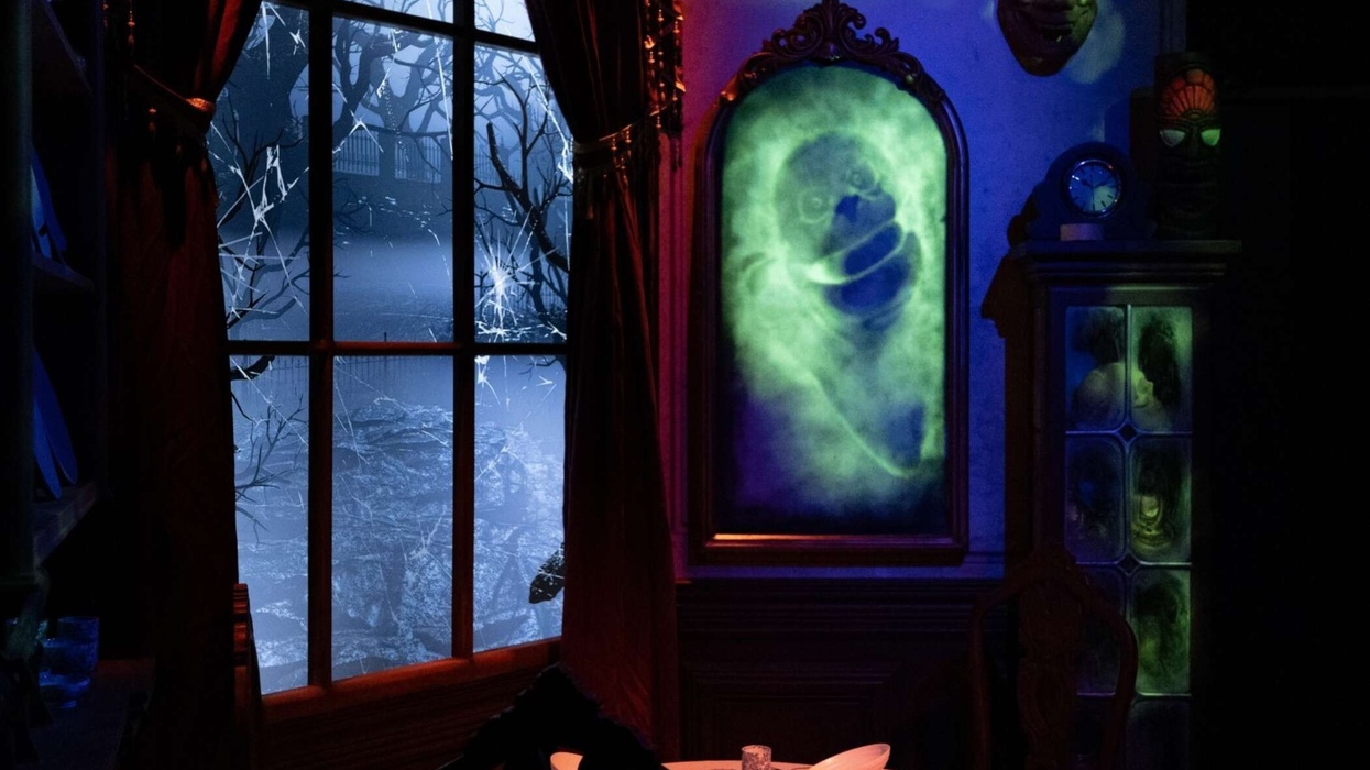 Spooky room with glowing ghost portrait, eerie masks, and moonlit window scene.