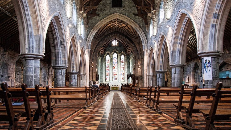 St Canice's Cathedral - Gothic cathedral interior with stone arches, stained glass, and wooden pews.