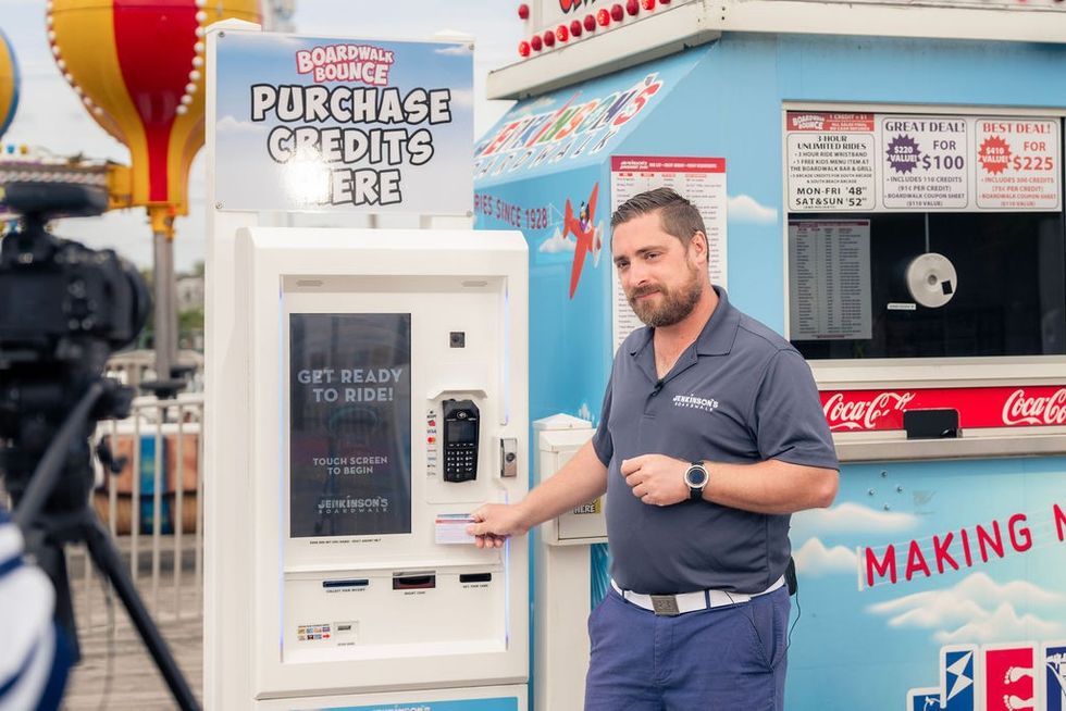 Staff demonstrating credit kiosk at a Jenkinson's Boardwalk amusement area.