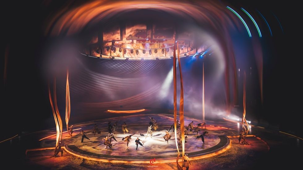 Stage performance named 'Terhal' with dancers, dynamic lighting, and tall, flowing banners.