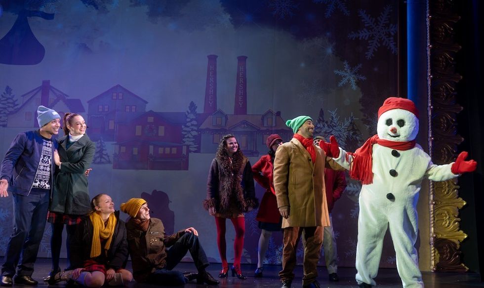 Stage play with actors in winter clothes and a person in a snowman costume.