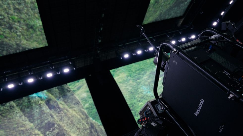 Stage setup with large screens displaying lush greenery; bright lights overhead.