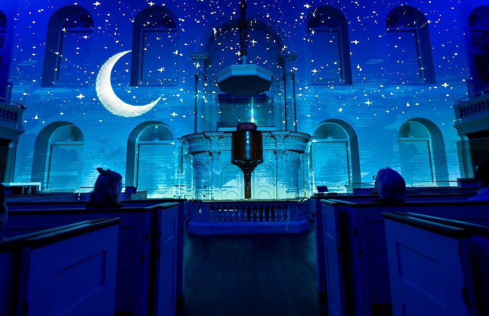 Starry night projection with crescent moon inside a church interior.