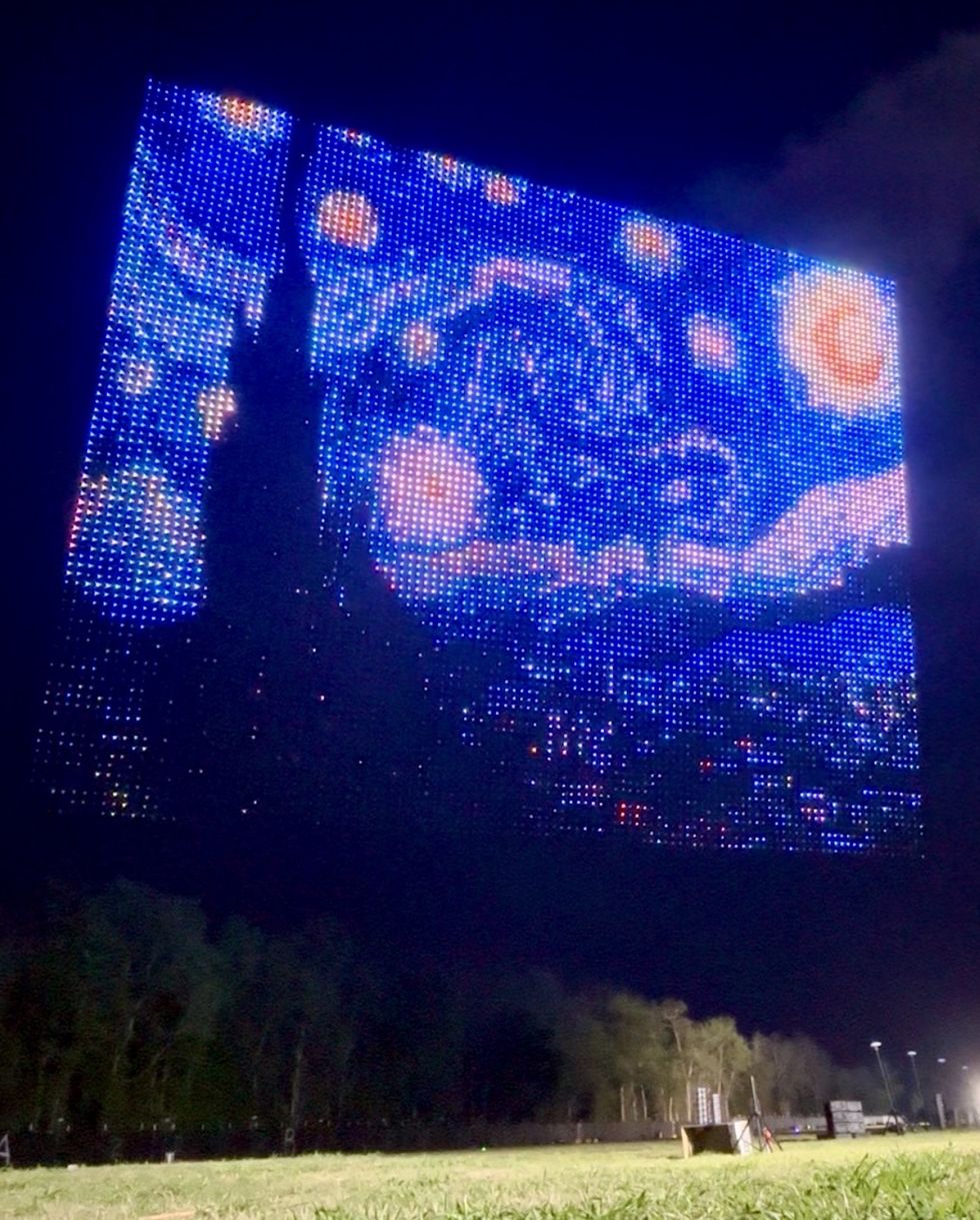 Starry Night recreated with lights in a large outdoor display at night.