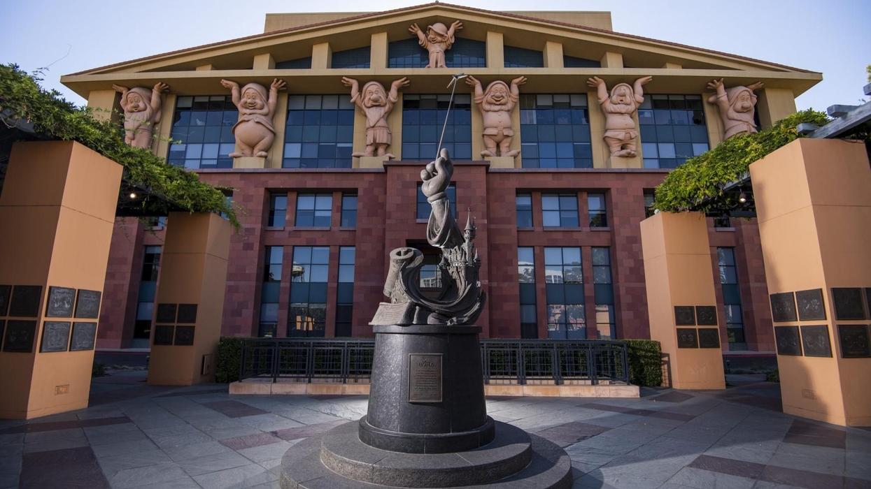 Statue of Mickey Mouse outside cartoon-themed building with Seven Dwarfs sculptures.