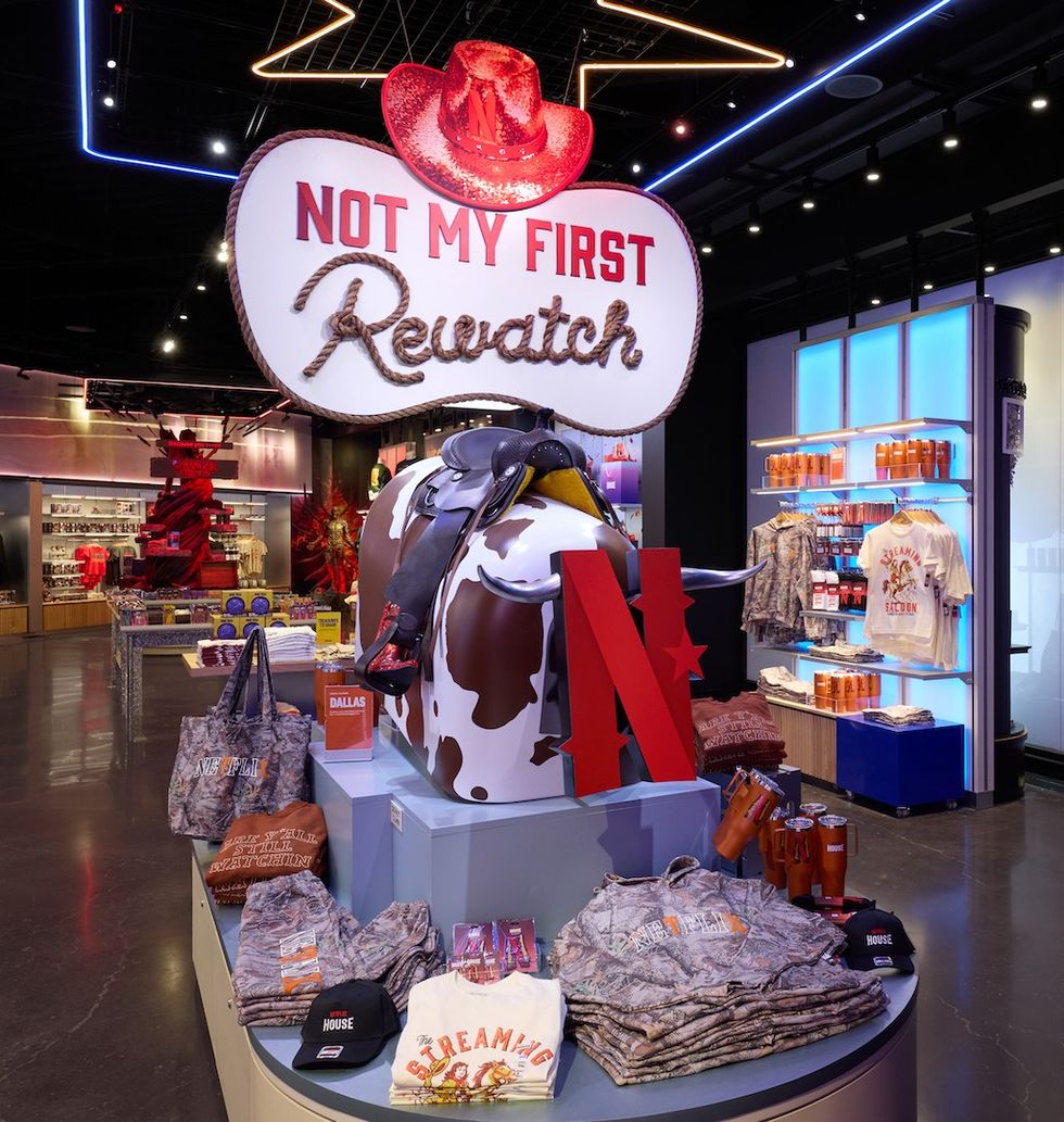 Store display with "Not My First Rewatch" sign, cowboy hat, and various merchandise.