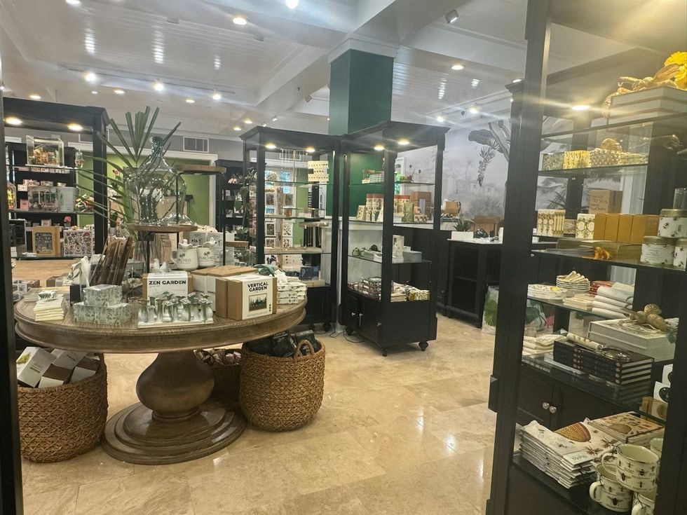 Store interior with a wooden table displaying garden-themed decor and gifts. The Sanctuary Shop at Fairchild Tropical Botanic Garden