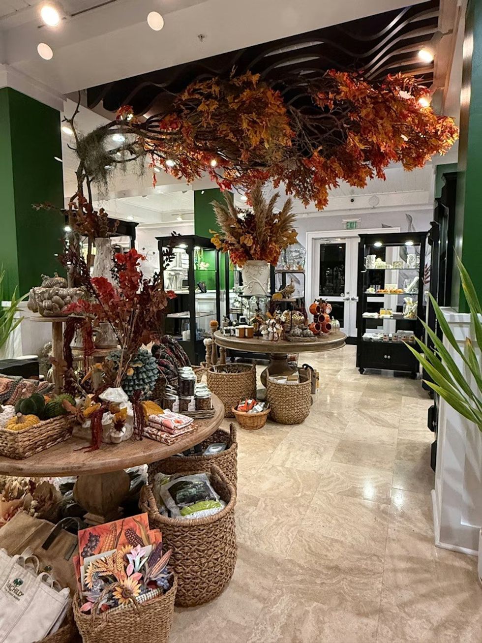Store interior with autumn decorations and various products in baskets on display tables. The Sanctuary Shop at Fairchild Tropical Botanic Garden