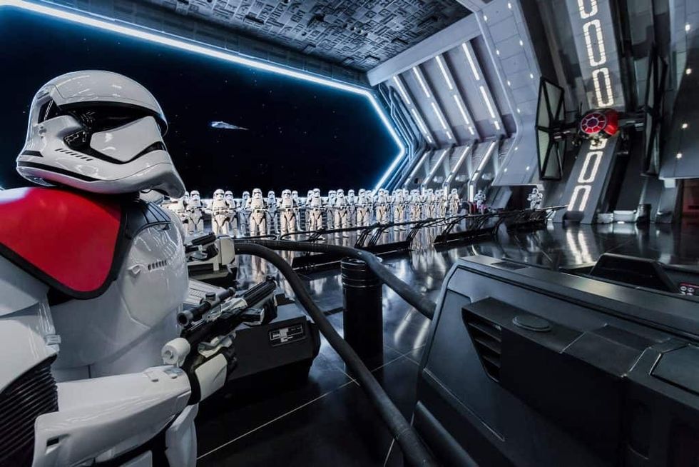 Stormtroopers stand in formation inside a futuristic hangar with a starry space view during Rise of the Resistance ride