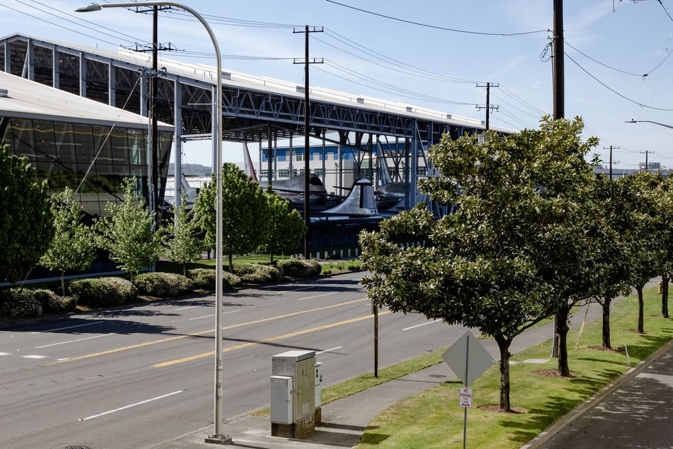 Street view at the Museum of Flight with trees and industrial buildings, including a covered shipyard structure.