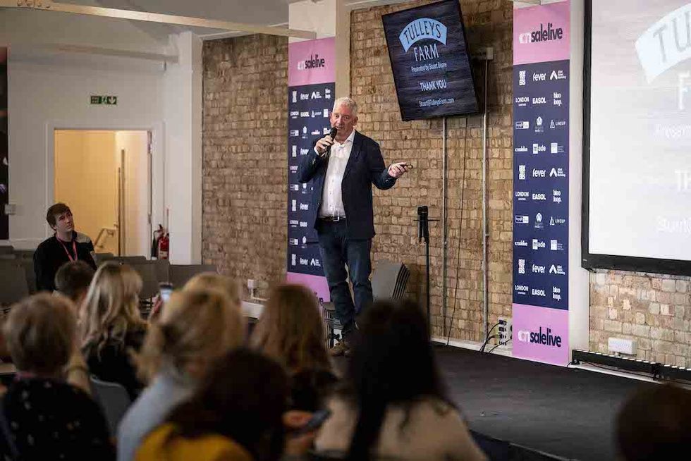 Stuart Beare speaking on stage at On Sale Live conference with attentive audience.