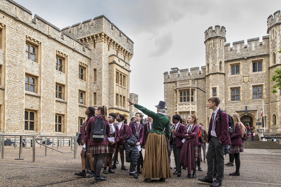 Students on a tour of the Tower of London with a guide in period costume.
