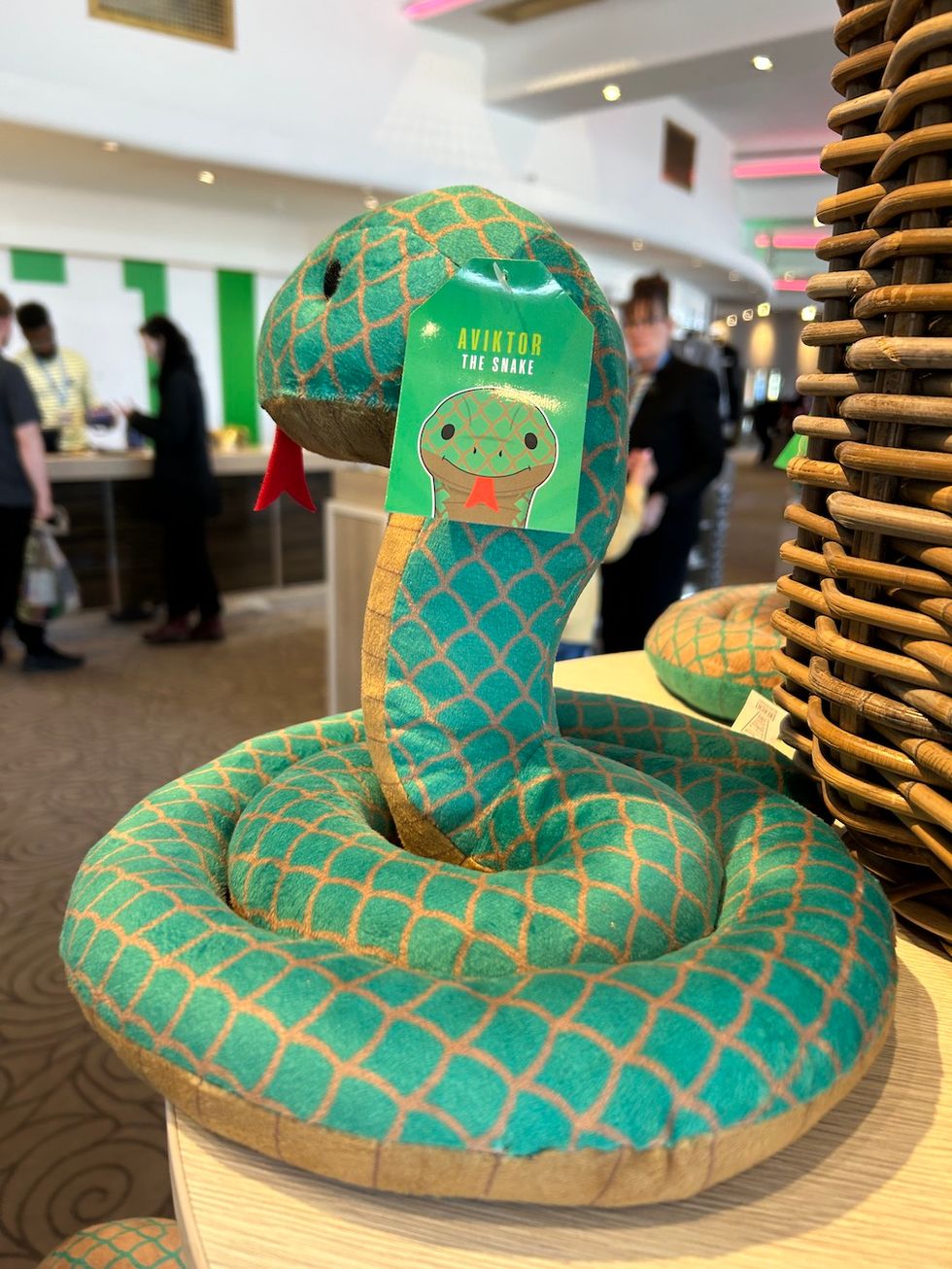 Stuffed green toy snake with tag reading "Aviktor the Snake" on a shelf display.