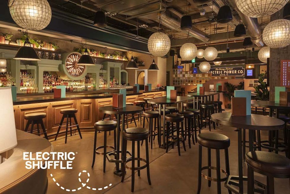 Styled bar interior with round tables, stools, and hanging globe lights.