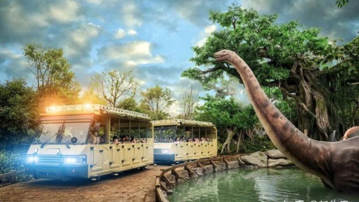 Super 78 ride Dino Tour trams going past animatronic dinosaur in rainforest