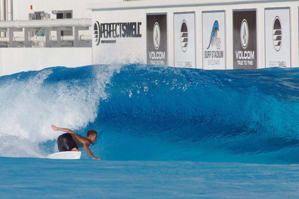 Surfer riding a blue wave at an artificial wave pool facility by PerfectSwell in Japan