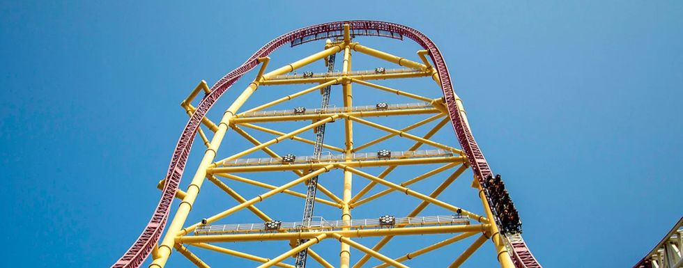 Tall roller coaster with steep drop and yellow structure against a clear blue sky at Cedar Point