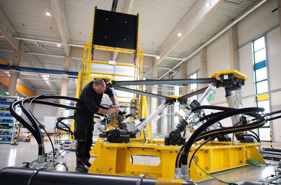 Technician working on industrial machinery in a spacious factory setting.