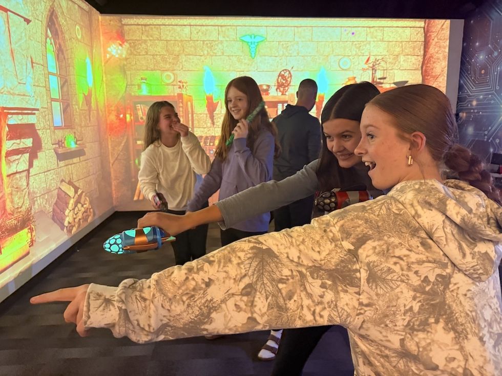 Teens laughing and playing an interactive game with colorful projections.