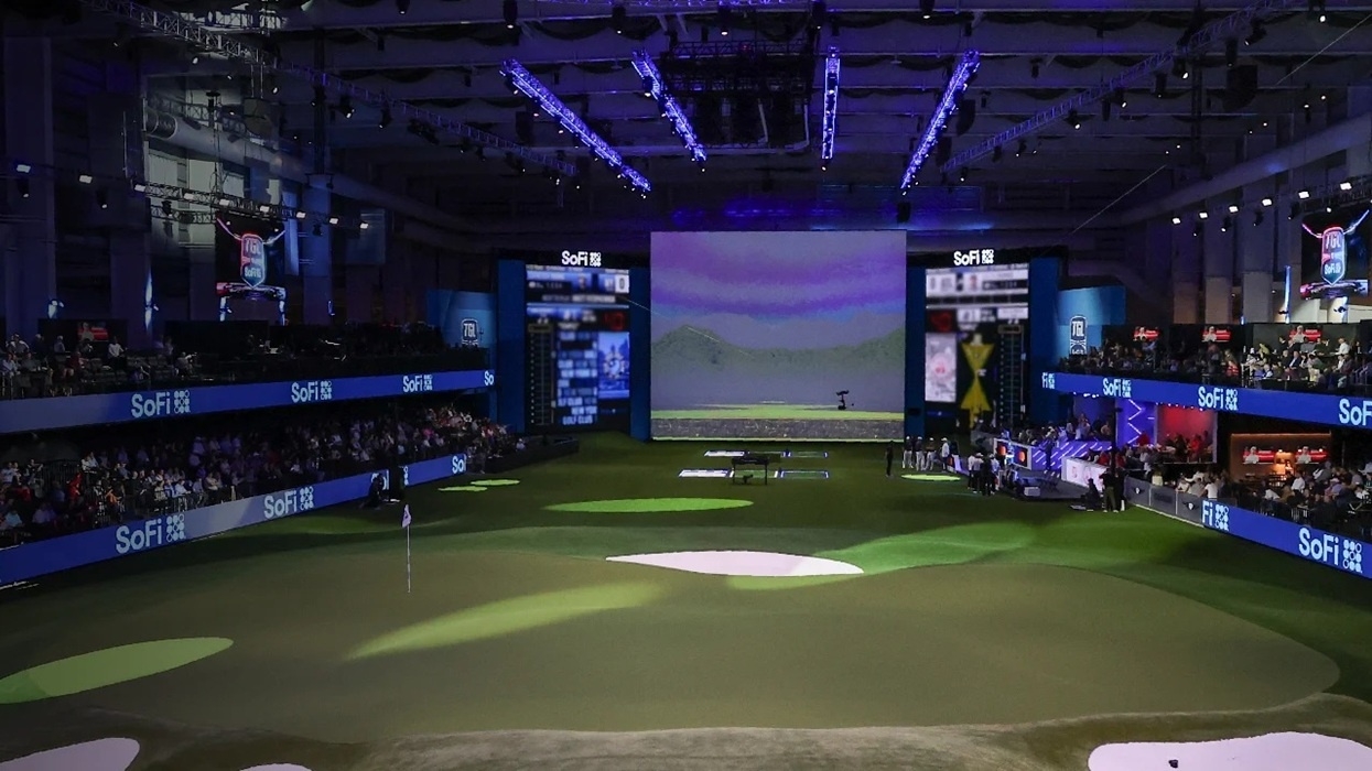 TGL presented by SoFi indoor golf course with digital screens and audience seating, lit by purple lights.