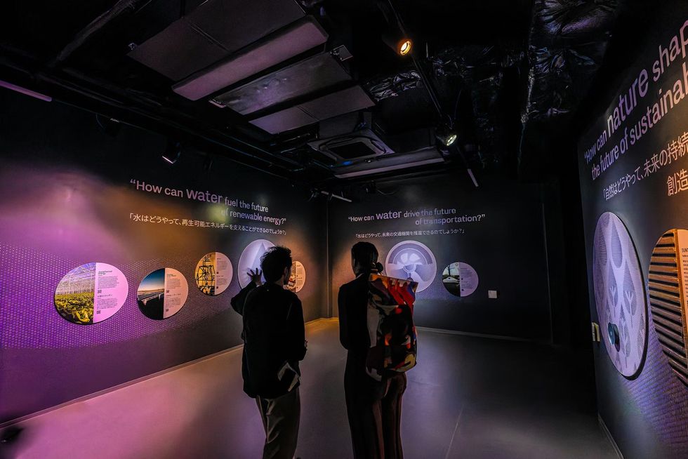 The Netherlands Pavilion at Expo 2025 Two people viewing exhibit on sustainable water and nature usage in a dimly lit room.