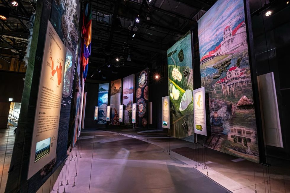 The Philippines Pavilion at Expo 2025 Artistic exhibit with large tapestry panels and informative displays in a dimly lit gallery.