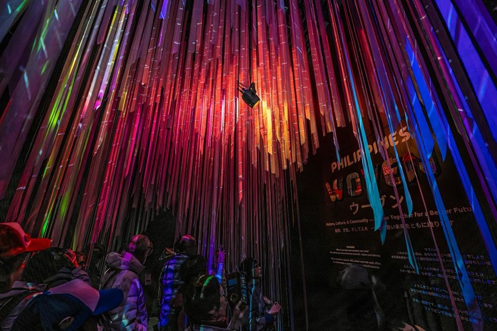 The Philippines Pavilion at Expo 2025 People explore a vibrant, multicolored light installation with hanging strips.