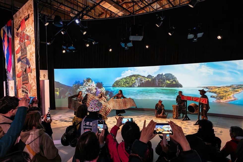 The Philippines Pavilion at Expo 2025 People watch a cultural performance with traditional attire and scenic island backdrop.
