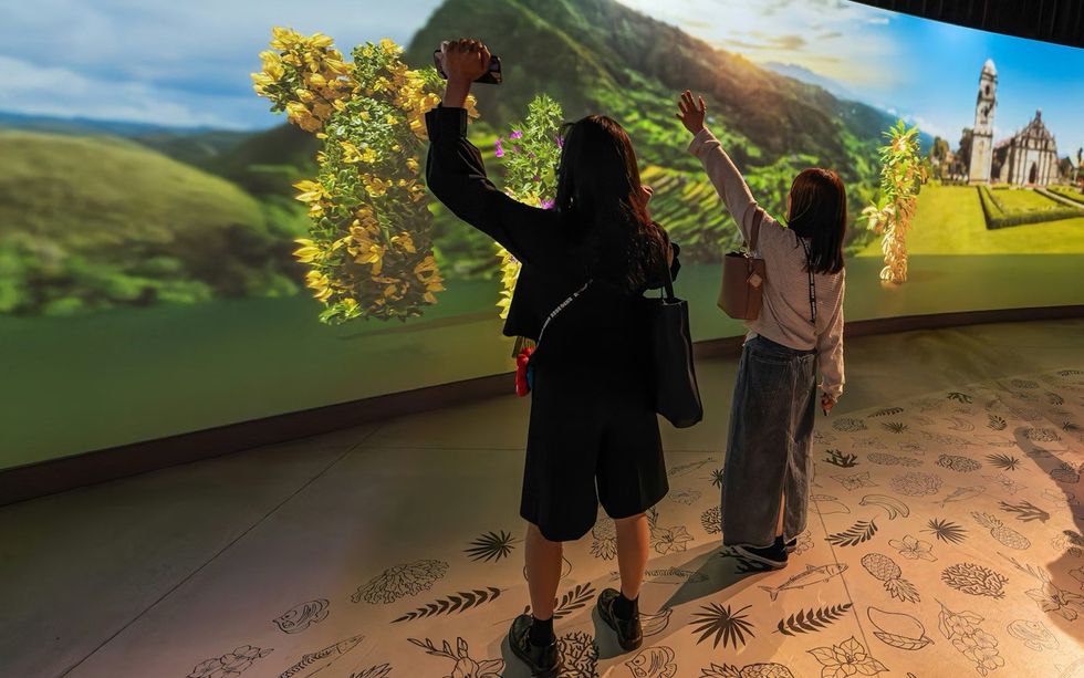 The Philippines Pavilion at Expo 2025 Two people interact with a colorful digital wall display featuring flowers and landscapes.