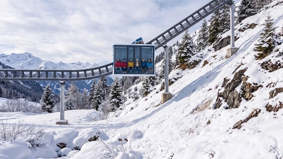 The PM360's glass cabin carrying passengers glides above a snowy mountain landscape.