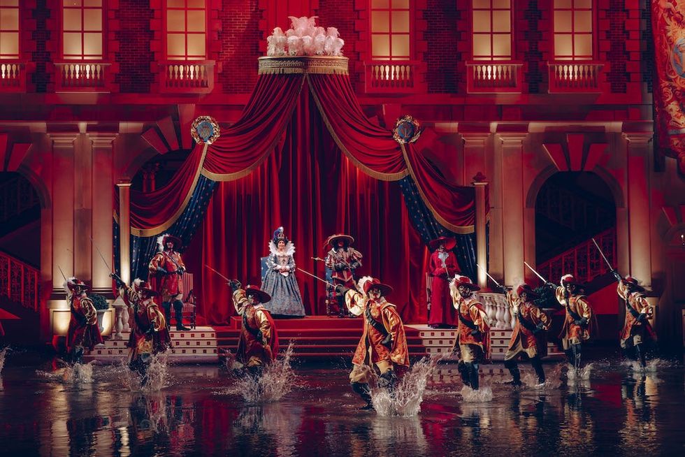 Theater stage for Mousquetaire de Richelieu at Puy du Fou with lavish costumes, red drapes, and actors splashing water.